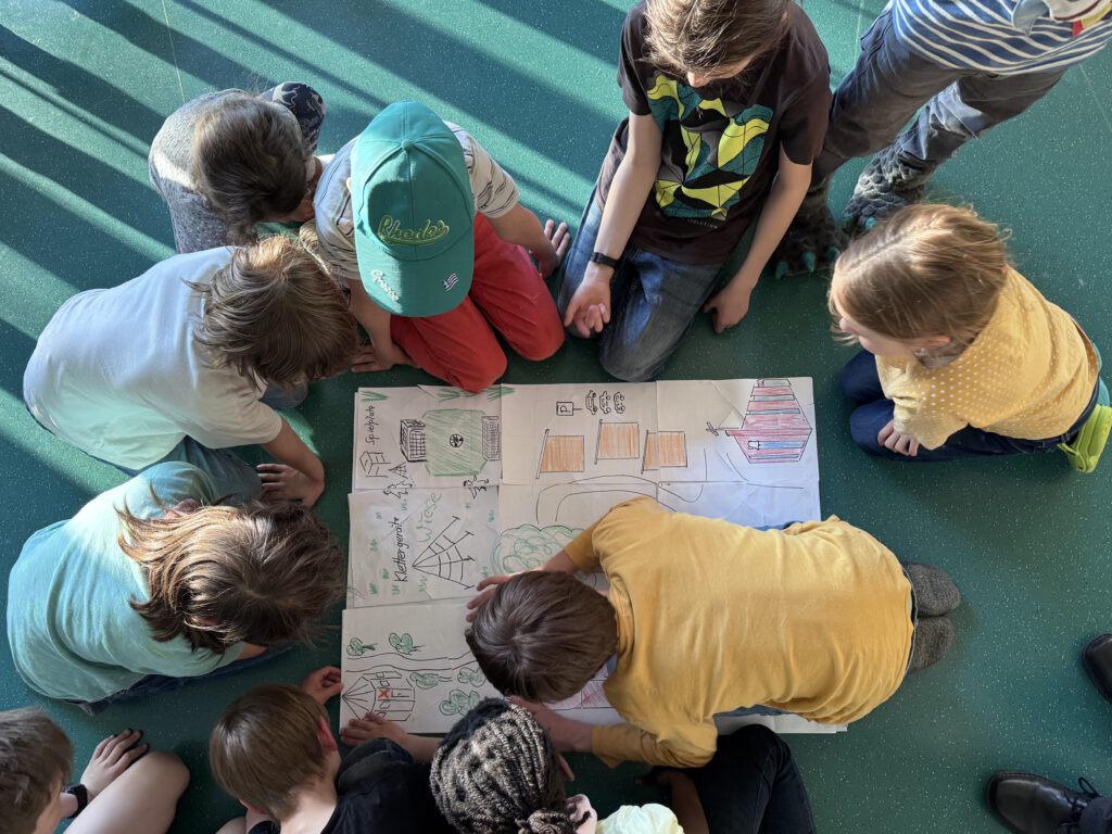 Kinder untersuchen eine gemalte Schatzkarte mit einem roten "X", wo der Schatz versteckt sein soll.
